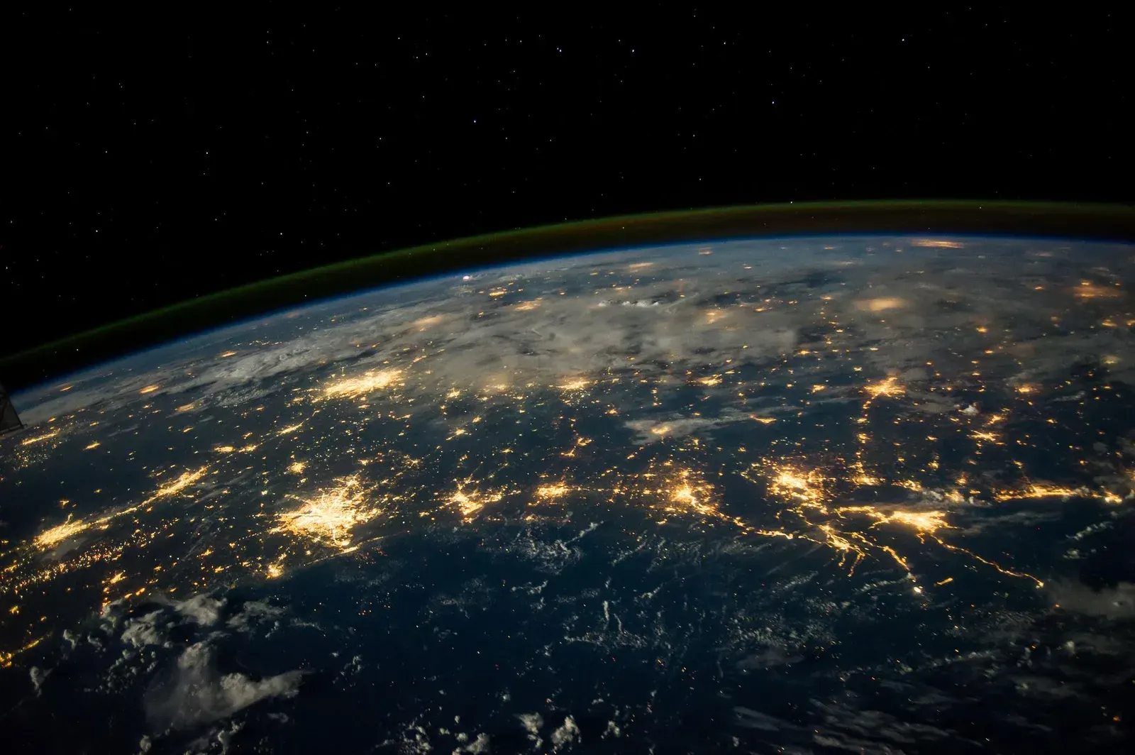 Earth at night seen from orbit, city lights tracing the continents